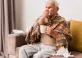 Idoso agasalhado com lenço e caneca apresenta sintomas respiratórios durante o frio.