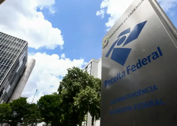 Placa da Receita Federal em frente a prédio público representando o pagamento da restituição do Imposto de Renda.