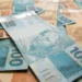 Cédulas de dinheiro brasileiro representando o pagamento de valores atrasados do INSS liberados pela Justiça Federal.