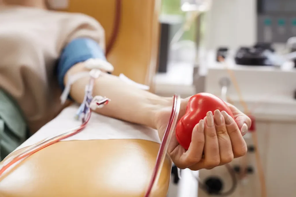Doação de sangue Mão de doador segura objeto em formato de coração durante coleta de sangue em hemocentro.