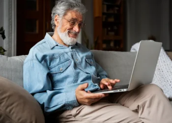 Idoso utilizando notebook em casa durante capacitação para uso seguro de ferramentas digitais.