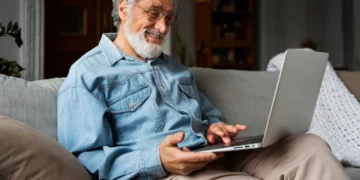 Idoso utilizando notebook em casa durante capacitação para uso seguro de ferramentas digitais.