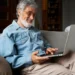 Idoso utilizando notebook em casa durante capacitação para uso seguro de ferramentas digitais.