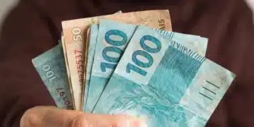 Mão segurando notas de real para representar o pagamento de aposentadorias e benefícios do INSS em agosto de 2026.