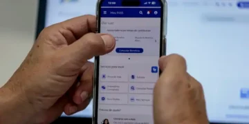 Pessoa acessa o aplicativo Meu INSS pelo celular para consultar e agendar serviços do INSS.