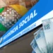 Imagem com fachada da Previdência Social, cédulas de real e elementos associados ao INSS.