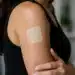 Mulher com adesivo transdérmico no braço representando o uso de reposição hormonal com testosterona.