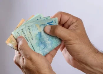 Mãos segurando notas de real.