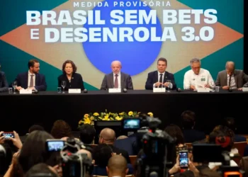 Lula assina a medida provisória do Desenrola 3.0 ao lado de ministros, durante coletiva com o painel "Brasil sem Bets e Desenrola 3.0" ao fundo.