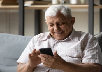 Idoso consulta no celular informações sobre restituição do Imposto de Renda.