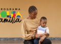 Mãe e filho sentados ao lado da logo do Bolsa Família.