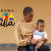 Mãe e filho sentados ao lado da logo do Bolsa Família.