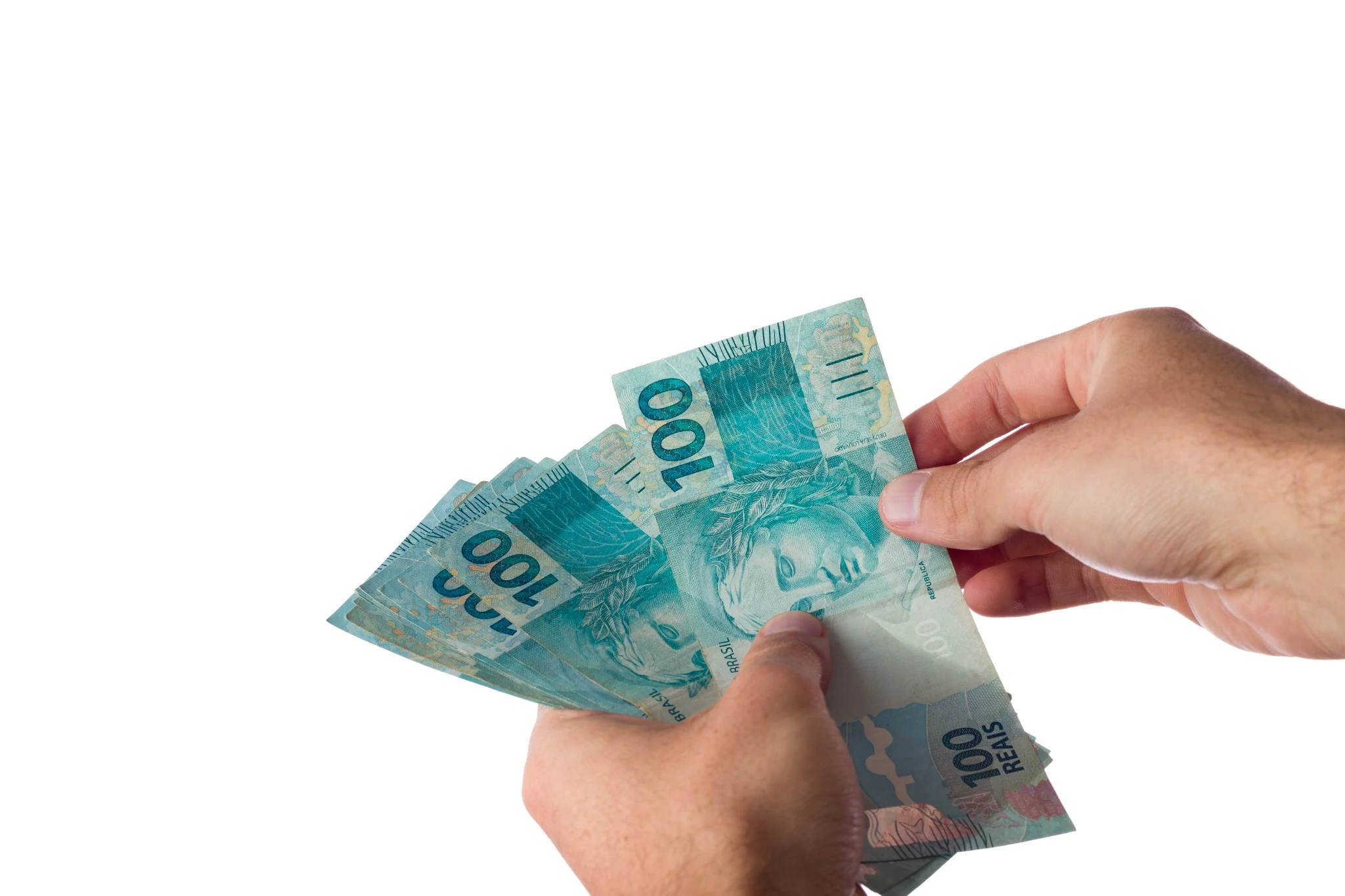 Pagamento lote residual. Mãos seguram cédulas de real referentes ao pagamento da restituição do Imposto de Renda.