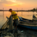 Pescador recolhendo rede ao pôr do sol.