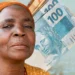 Mulher segurada do INSS segura notas de dinheiro representando a aposentadoria por idade e o recebimento de benefício previdenciário.