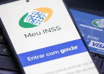 Aplicativo Meu INSS em celular representa o agendamento de perícias médicas e avaliações sociais.