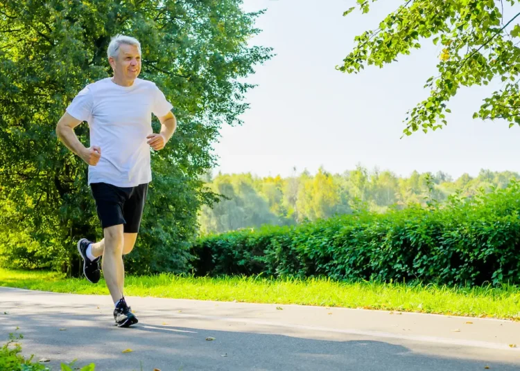 Idoso pratica corrida ao ar livre em parque arborizado como exemplo de cuidado com a saúde e qualidade de vida após os 60 anos.