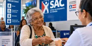 Mulher idosa sorridente entrega documento a uma atendente em balcão de atendimento prioritário, com sinalização do SAC ao fundo.