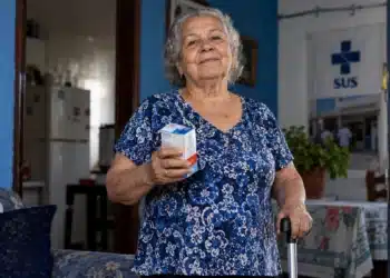 Pessoa idosa segura medicamentos e utiliza bengala em referência aos direitos garantidos pelo Estatuto da Pessoa Idosa no SUS.