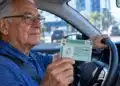 Motorista com mais de 70 anos segura a CNH dentro do carro