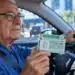 Motorista com mais de 70 anos segura a CNH dentro do carro