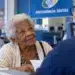 Idosa com mais de 80 anos sendo atendida em órgão público, representando a prioridade especial garantida a esse grupo.