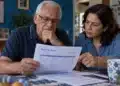 Idoso brasileiro e familiar analisam documento do plano de saúde sobre a mesa, em referência às regras de reajuste por data de contratação.